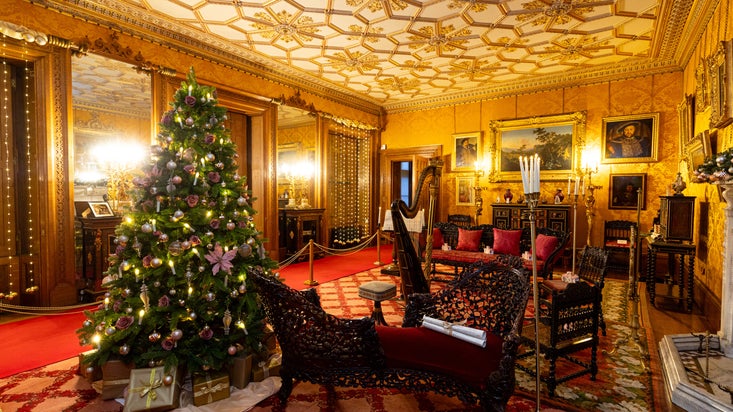 A Christmas tree with soft pink decorations stands in the golden Drawing Room